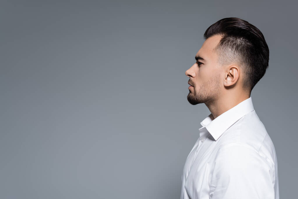 vista lateral del hombre de negocios barbudo en camisa blanca aislada en gris - Foto, Imagen