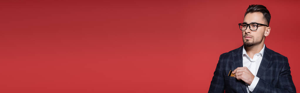 бородатий бізнесмен в блістері і окулярах кладе кредитну картку в кишеню на червоний, банер
 - Фото, зображення