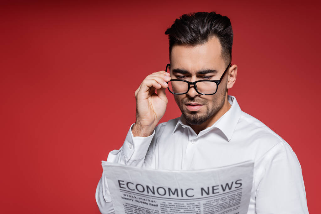 bärtiger Geschäftsmann im weißen Hemd, der eine Brille aufsetzt und Nachrichten auf Rot liest - Foto, Bild