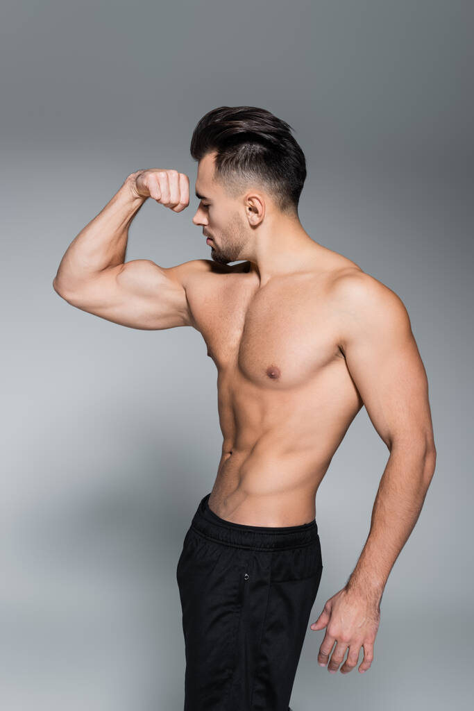 deportista sin camisa y musculoso mostrando músculos en gris - Foto, imagen