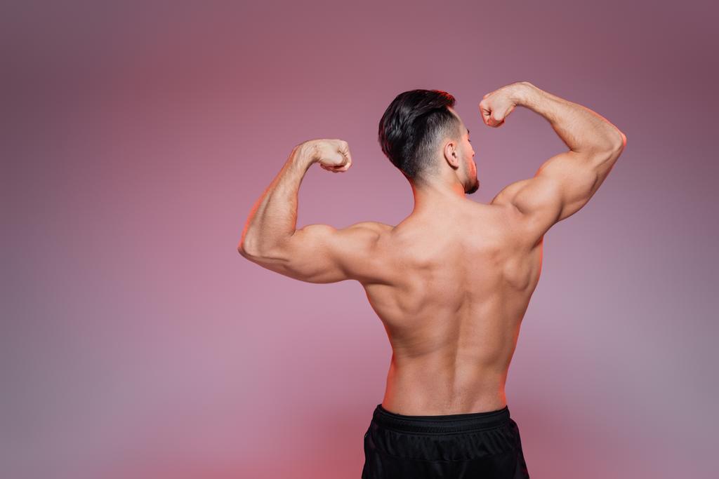 vista posterior del deportista sin camisa mostrando músculos en rosa y gris   - Foto, Imagen