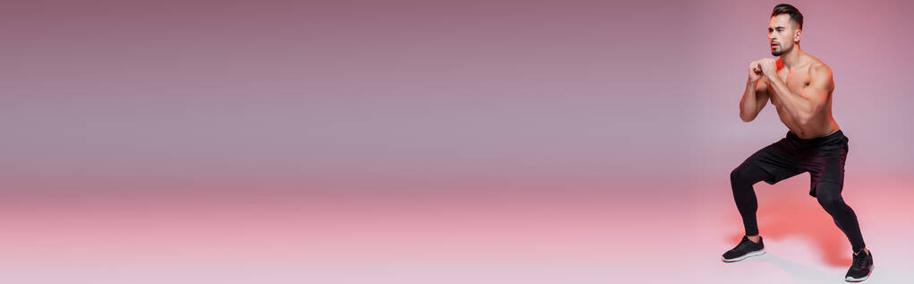 teljes hossza félmeztelen sportoló csinál guggolás gyakorlat szürke és rózsaszín, banner - Fotó, kép