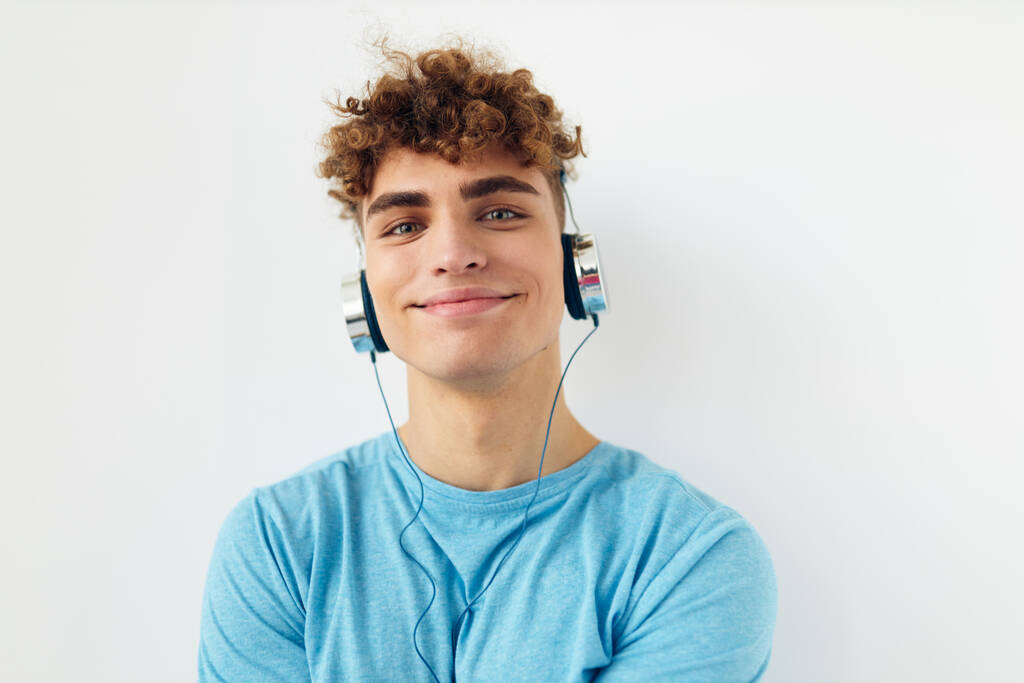 όμορφος άντρας με μπλε t-shirts ακουστικά φως μόδας φόντο - Φωτογραφία, εικόνα