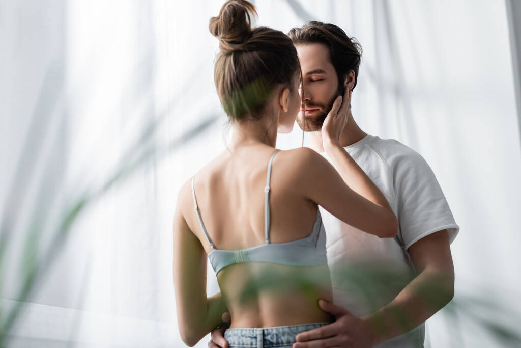 back view of woman in bra and bearded man hugging at home - Photo, Image