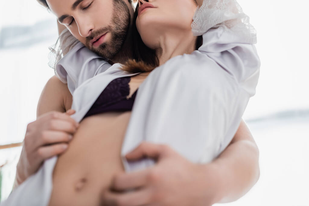 hombre barbudo seduciendo a mujer joven en ropa interior y bata de seda - Foto, Imagen