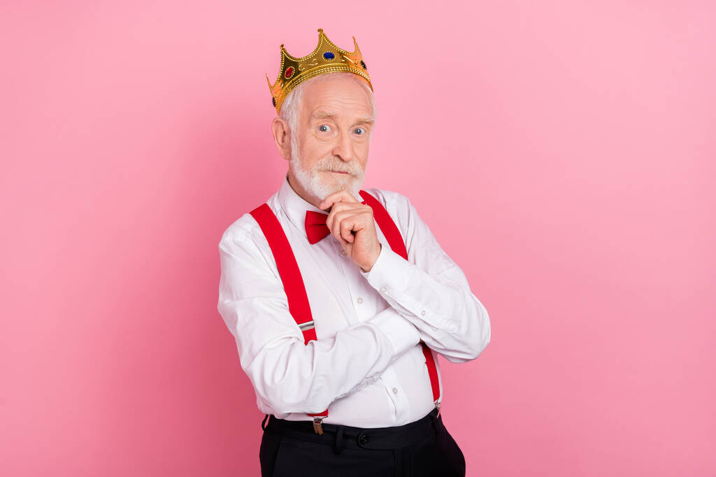 Portrait of attractive minded gray-haired man wearing tiara deciding isolated over pink pastel color background - Photo, Image
