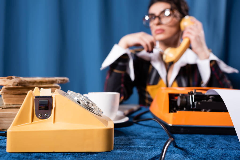 valikoiva painopiste vintage puhelin lähellä hämärtynyt uutisnainen puhuu sinisellä taustalla - Valokuva, kuva