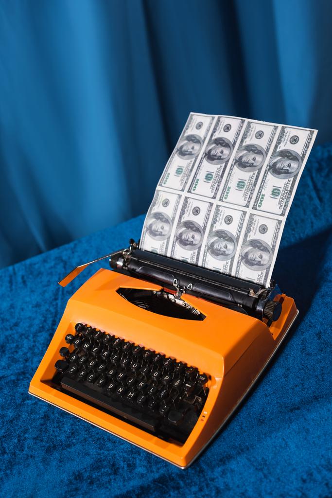 Vintage-Schreibmaschine und Dollarnoten auf Velours-Tischdecke und blauem Hintergrund - Foto, Bild
