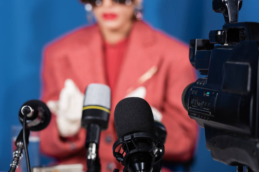 Mikrofonların ve kameranın yakın görüntüsü bulanık arka planda röportaj yapan kesilen kadının yanında. - Fotoğraf, Görsel