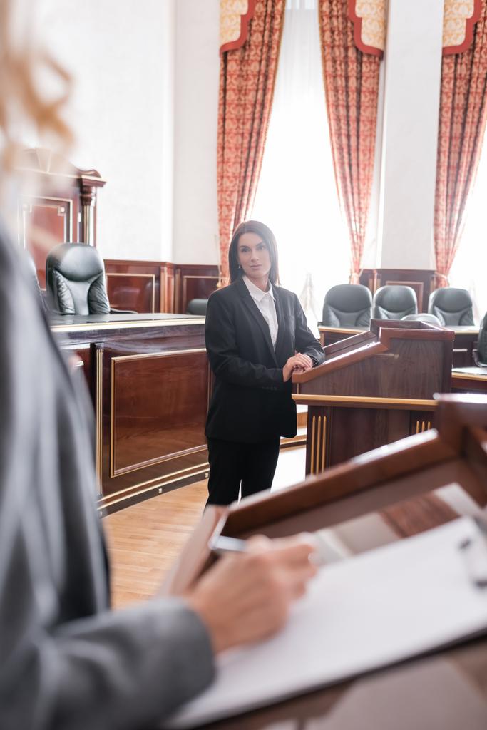 брюнетка свідок дивиться на розмитий адвокат під час судового розгляду
 - Фото, зображення