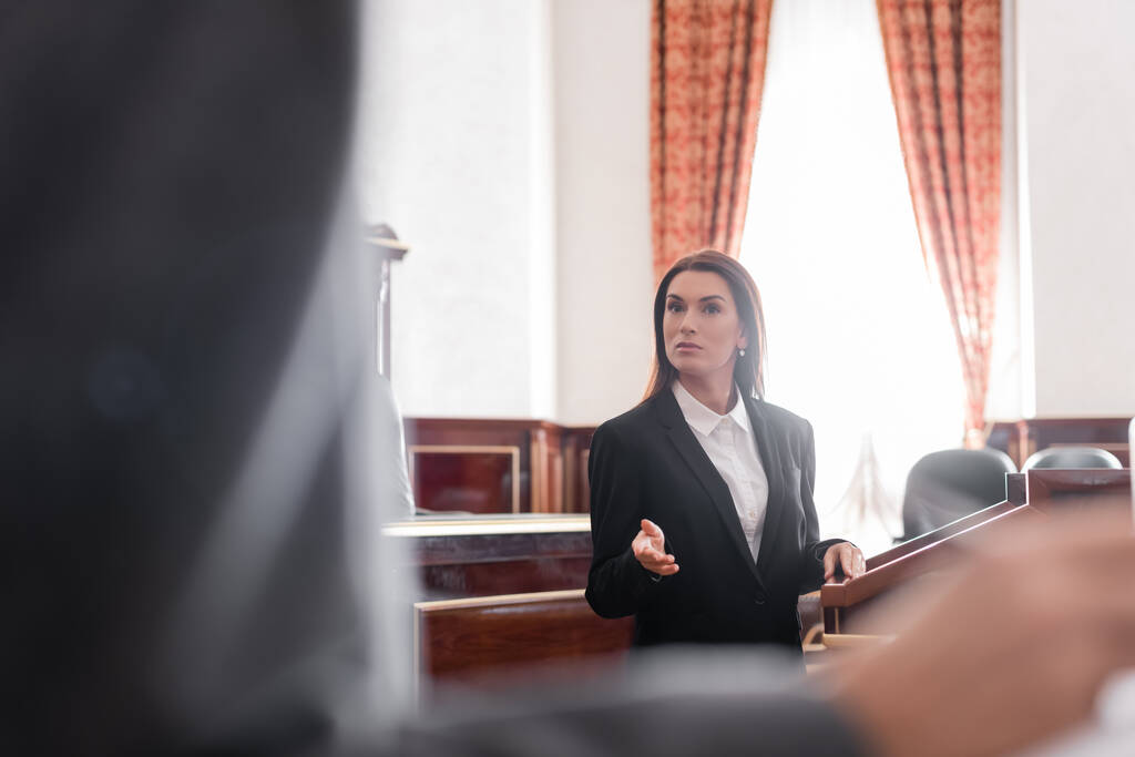 fiscal morena señalando con la mano mientras habla con testigo borroso en la sala del tribunal - Foto, Imagen