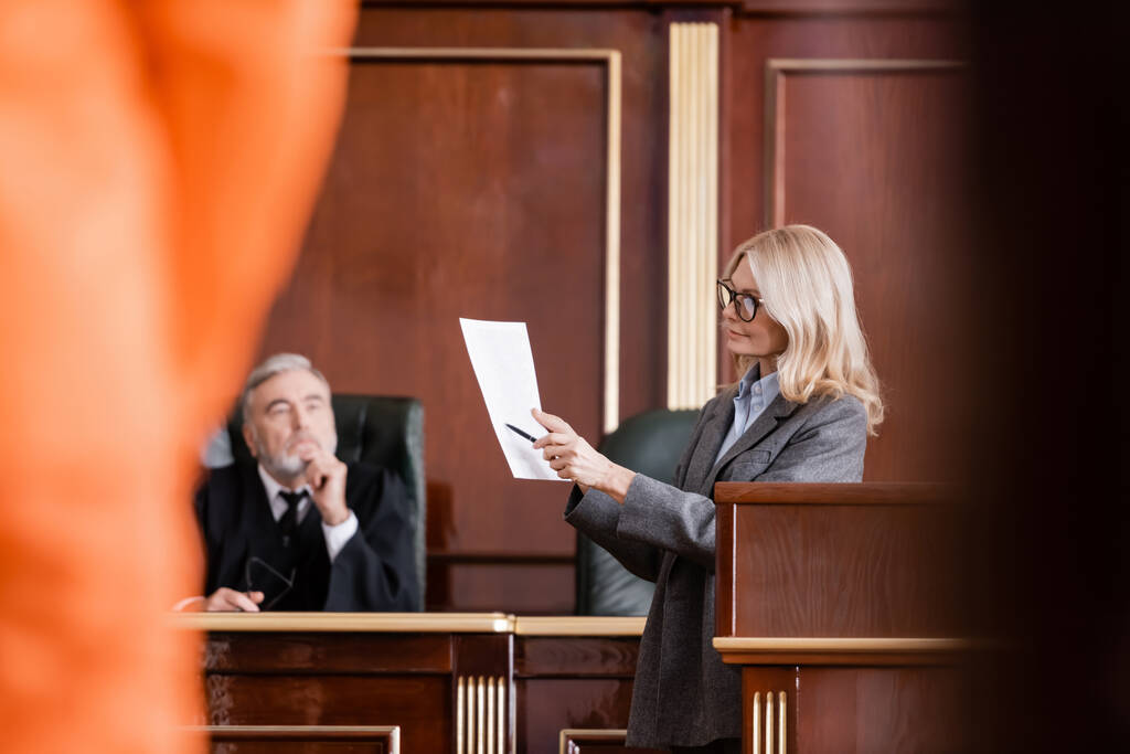 abogada rubia señalando la demanda cerca del juez en la sala del tribunal en primer plano borrosa - Foto, imagen