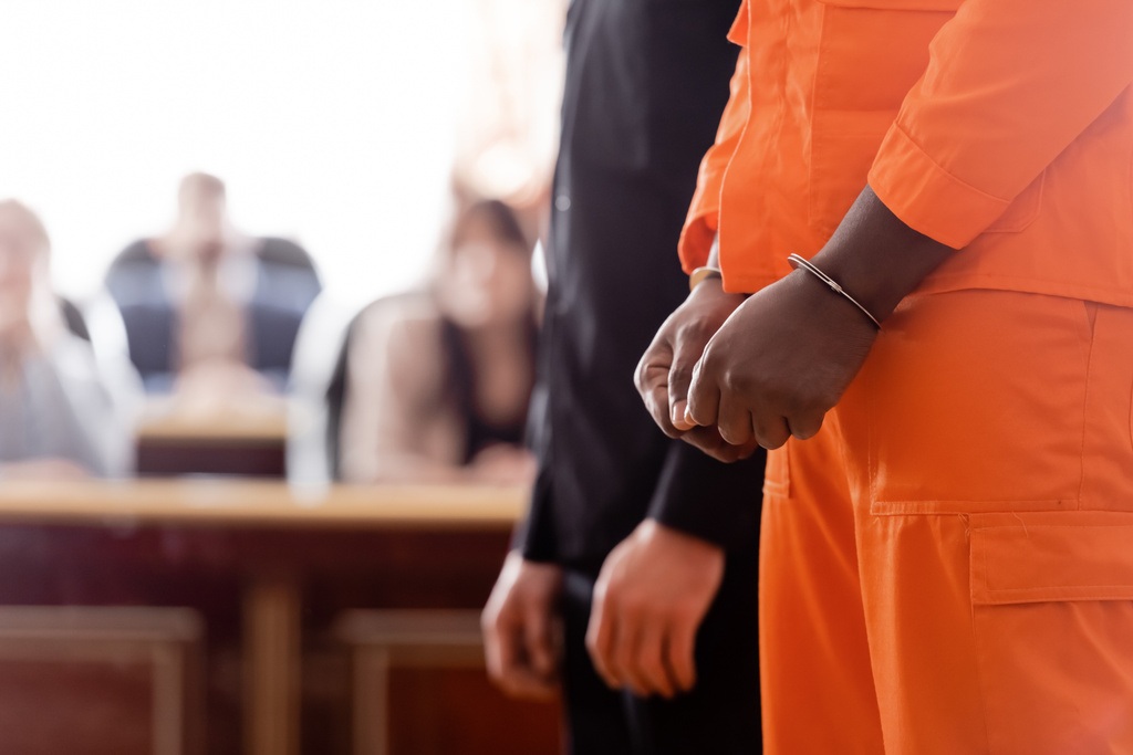 Osittainen näkemys käsiraudoissa afrikkalainen amerikkalainen mies ja ulosottomiehen lähellä hämärtynyt valamiesten oikeudessa - Valokuva, kuva
