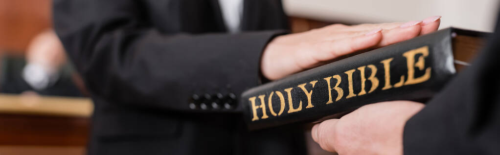cropped view of woman giving swear on bible in court during litigation, banner - Photo, Image