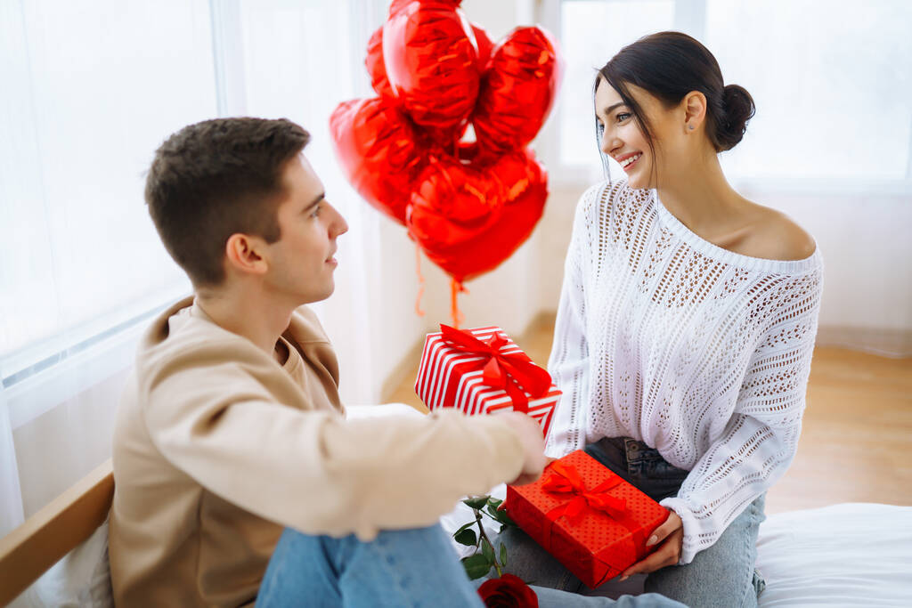 Koncept Valentýna. Milenci si dávají dárky. Mladý pár doma slaví Valentýna. - Fotografie, Obrázek