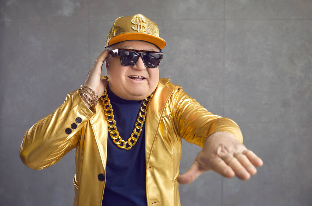 Lustiger Senior in goldener Jacke, Baseballkappe und Kettenkette spielt Musik bei Disco-Party - Foto, Bild