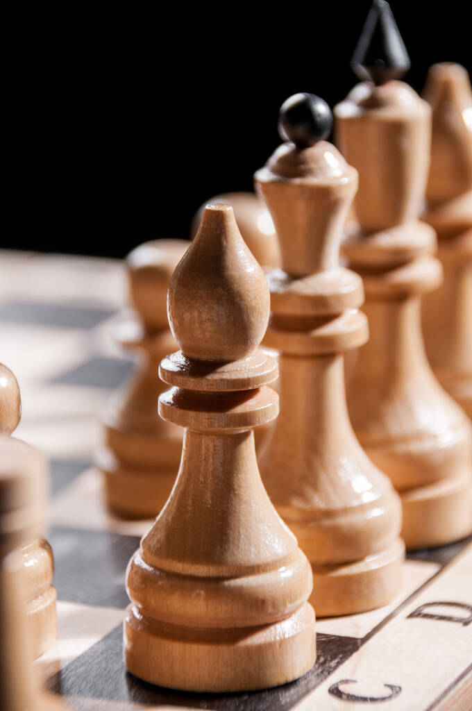 Witte schaakstukken op een schaakbord op een zwarte achtergrond, bordspel - Foto, afbeelding