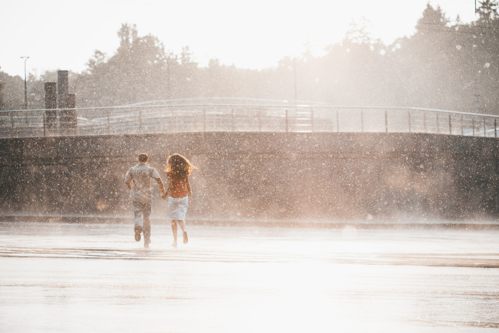Menina com o menino correr sob uma chuva para baixo
 - Foto, Imagem