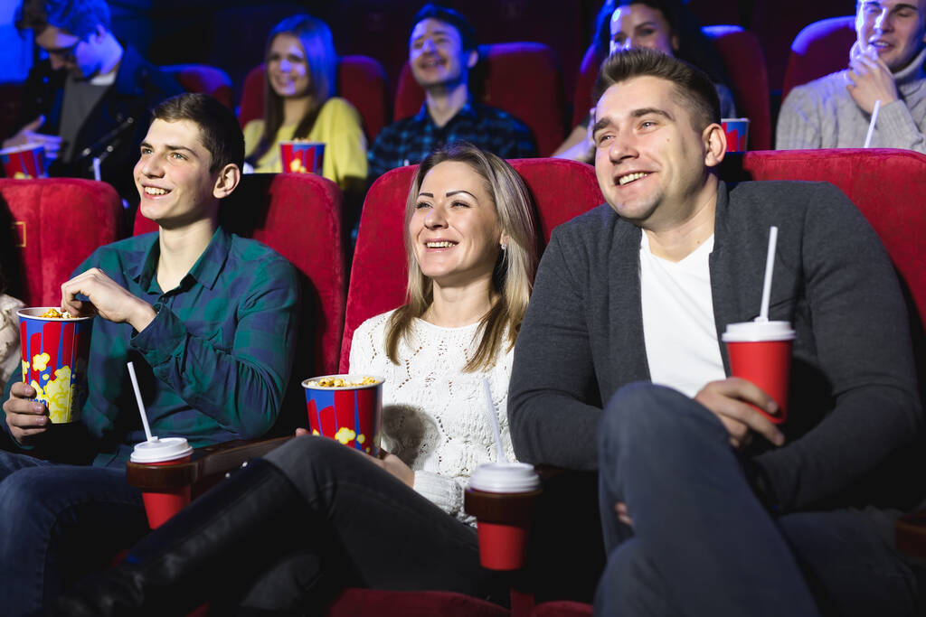 Gli amici si siedono e mangiano popcorn insieme mentre guardano film in un cinema
. - Foto, immagini