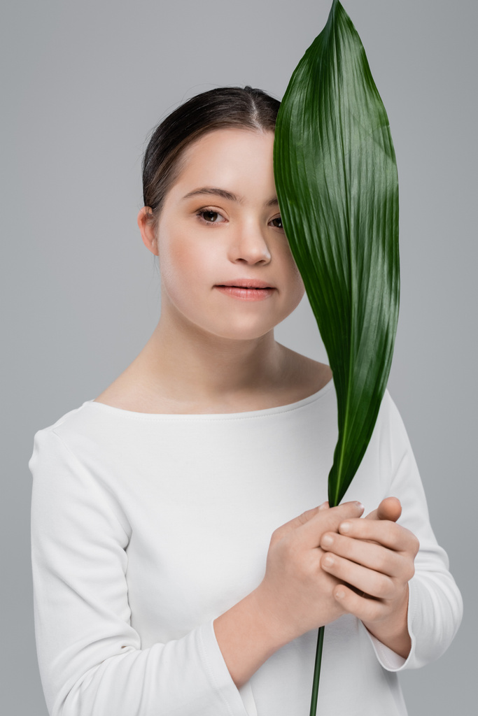 Woman with down syndrome holding leaf isolated on grey  - Photo, Image