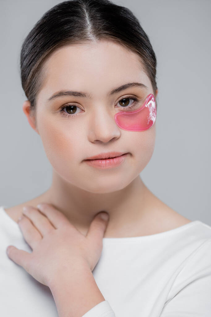Woman with down syndrome and eye patch looking at camera isolated on grey  - Photo, Image