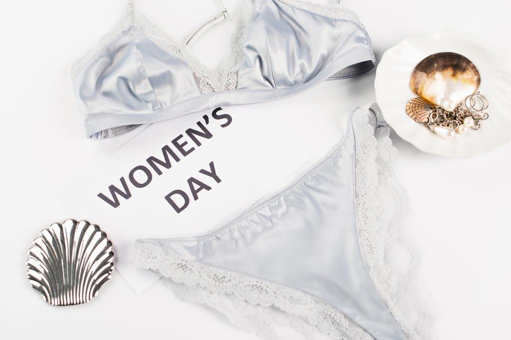 Bovenaanzicht van de kaart met vrouwen dag belettering in de buurt lingerie en accessoires op witte achtergrond  - Foto, afbeelding