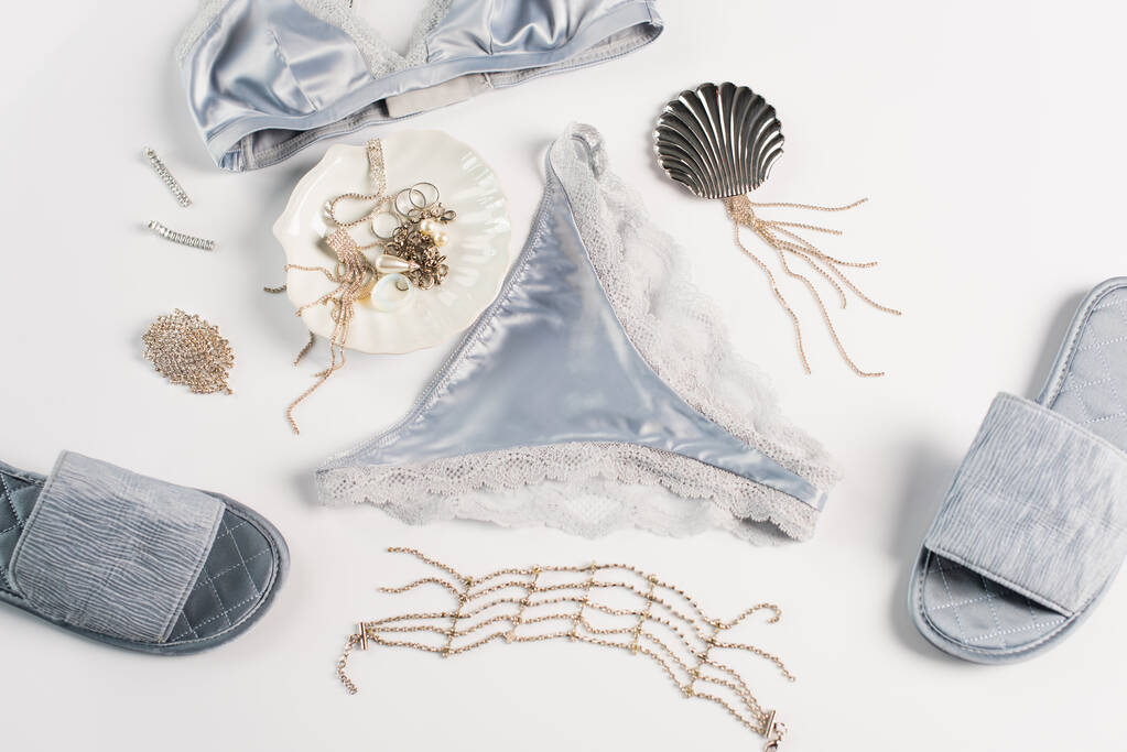 Bovenaanzicht van blauwe lingerie, slippers en accessoires op witte achtergrond  - Foto, afbeelding