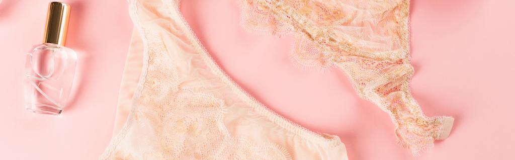 Vista superior de lingerie pêssego perto de perfume no fundo rosa, banner  - Foto, Imagem