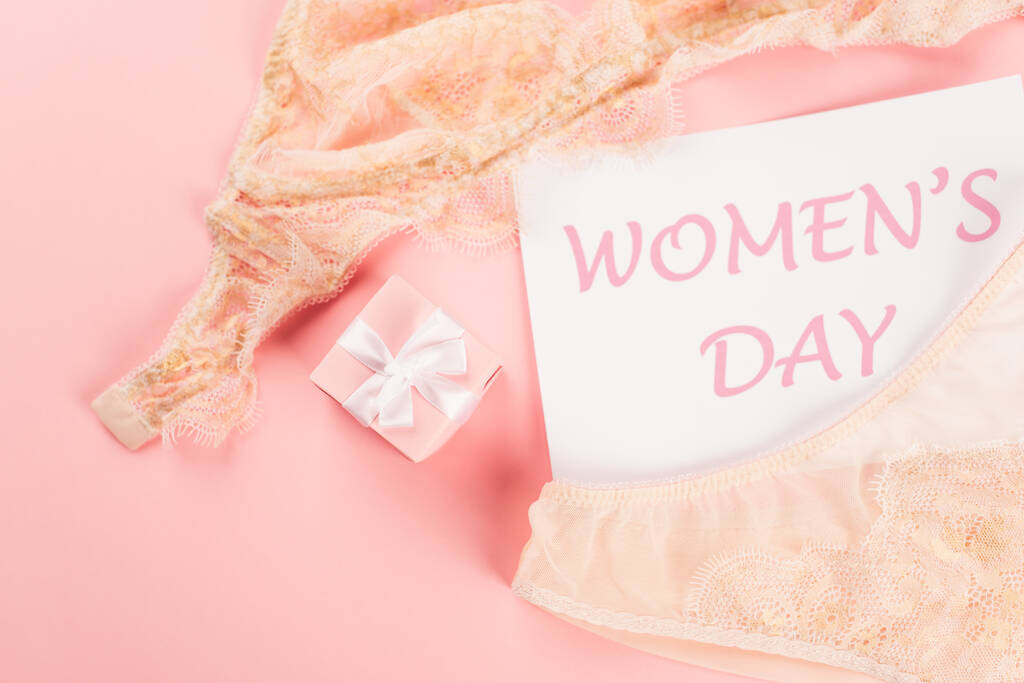 Вид сверху на открытку с женским дневным лежанием рядом с бельем и на розовом фоне  - Фото, изображение