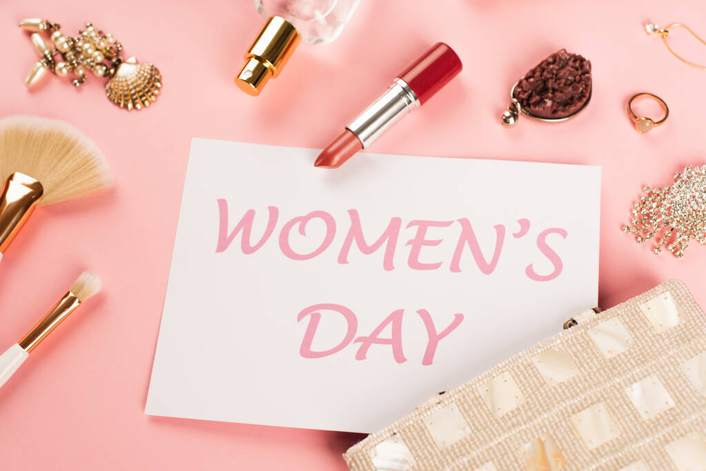 Top view of card with womens day lettering near perfume and accessories on pink background  - Photo, Image