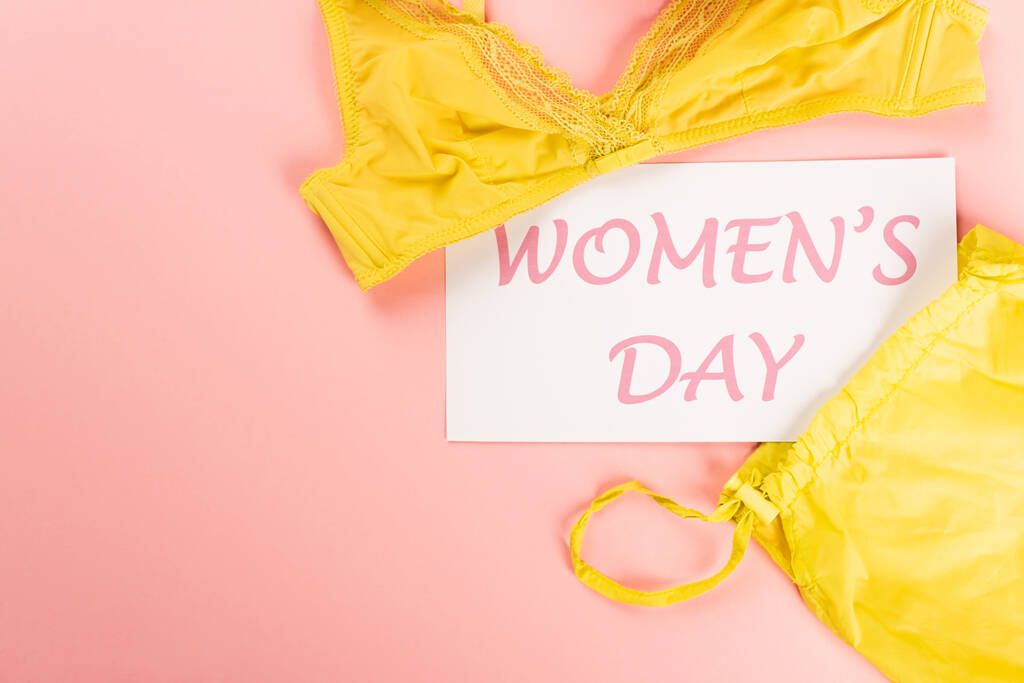 Vista dall'alto della carta con scritte giorno delle donne vicino al reggiseno su sfondo rosa  - Foto, immagini