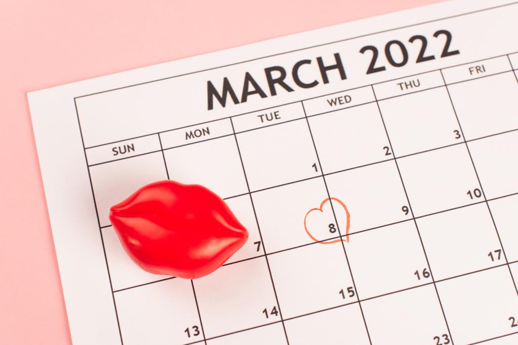 Вид сверху мартовского календаря со знаком сердца на розовом фоне  - Фото, изображение
