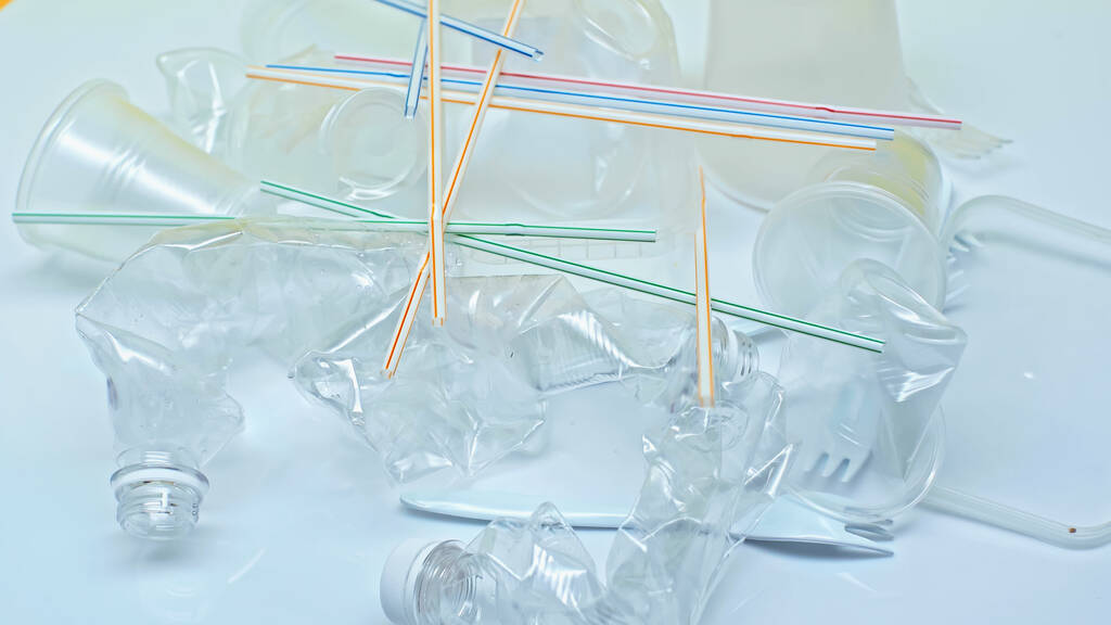 vasos de plástico cerca de tenedores y pajitas de colores en blanco - Foto, Imagen