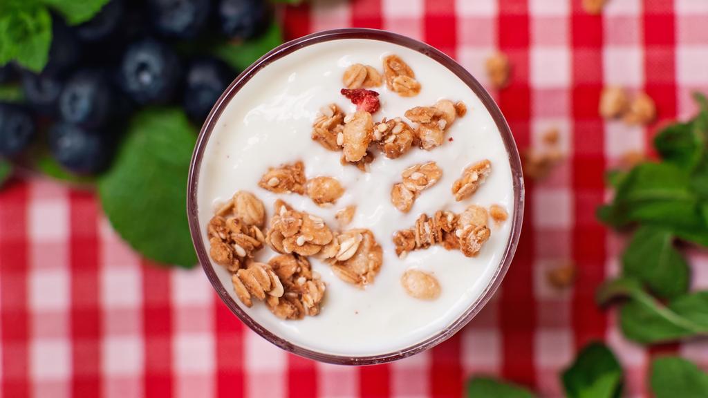 bovenaanzicht van knapperige granola bovenop verse yoghurt in glas  - Foto, afbeelding