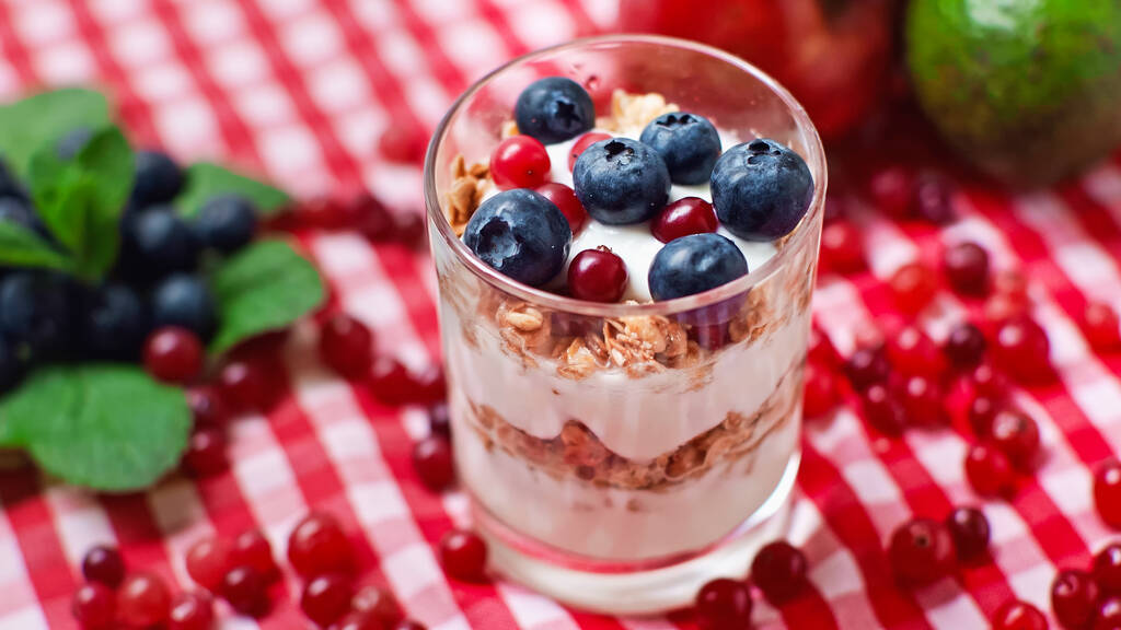 warstwy jogurtu i granoli z żurawiną i jagodami na wierzchu  - Zdjęcie, obraz