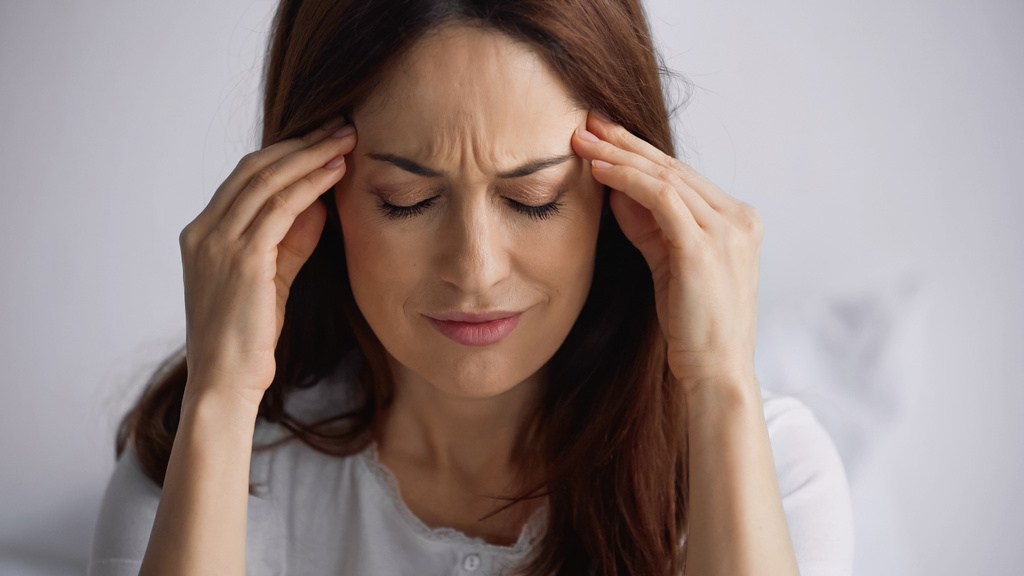 donna esausta con gli occhi chiusi che toccano la testa mentre soffre di emicrania su sfondo grigio - Foto, immagini
