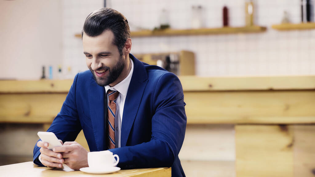 empresário alegre em mensagens terno no smartphone no café - Foto, Imagem