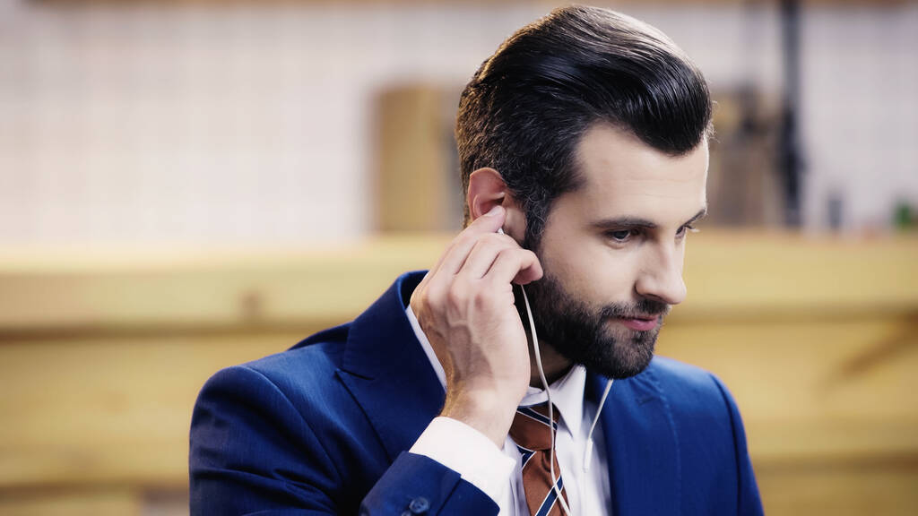 bebaarde zakenman in formele kleding aanpassen oortelefoon  - Foto, afbeelding