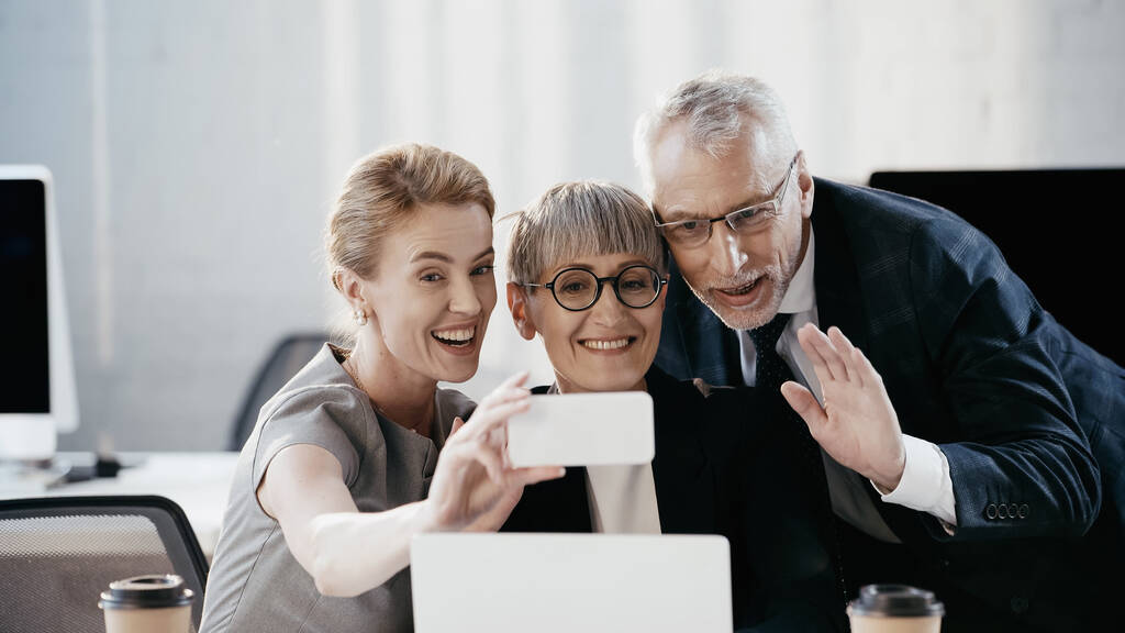 Lächelnde Geschäftsleute mit Videoanruf auf dem Smartphone im Büro  - Foto, Bild