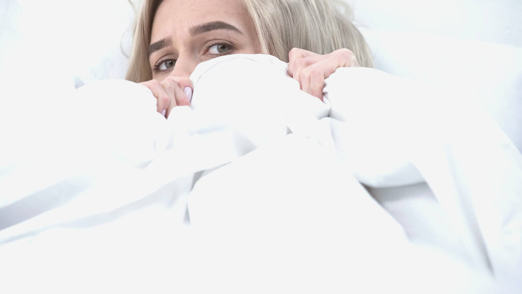 young blonde woman covering with blanket in bedroom  - Photo, Image