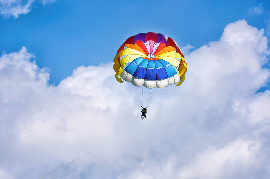 Parapente usando un paracaídas en el fondo del cielo azul nublado. - Foto, imagen