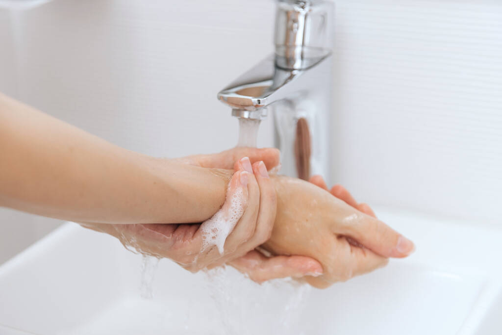 Se laver les mains sous le robinet d'eau courante. Se laver les mains en frottant avec du savon pour prévenir le virus de la couronne, l'hygiène pour arrêter la propagation du virus de la couronne dans les toilettes publiques. Concept d'hygiène détail des mains - Photo, image