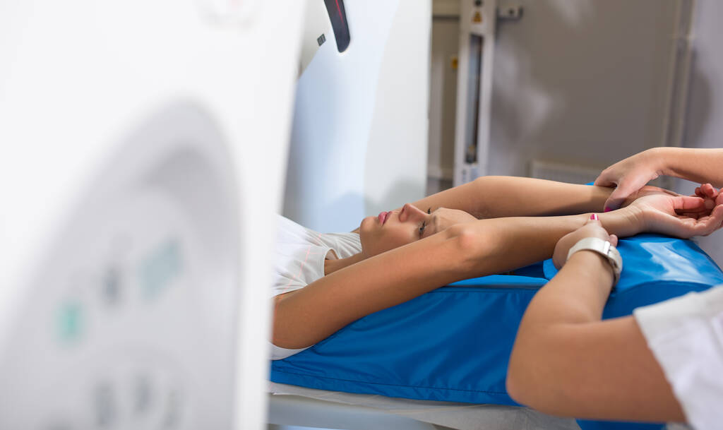 Ładna, młoda kobieta przechodzi komputerową tomografię osiową (CAT) Skanuj testy medyczne / badania w nowoczesnym szpitalu (kolorowy obraz; płytki DOF) - Zdjęcie, obraz