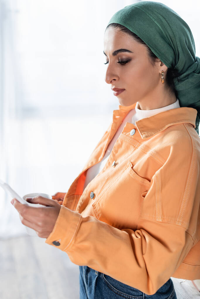 молода мусульманка в головному повідомленні на смартфоні вдома
 - Фото, зображення