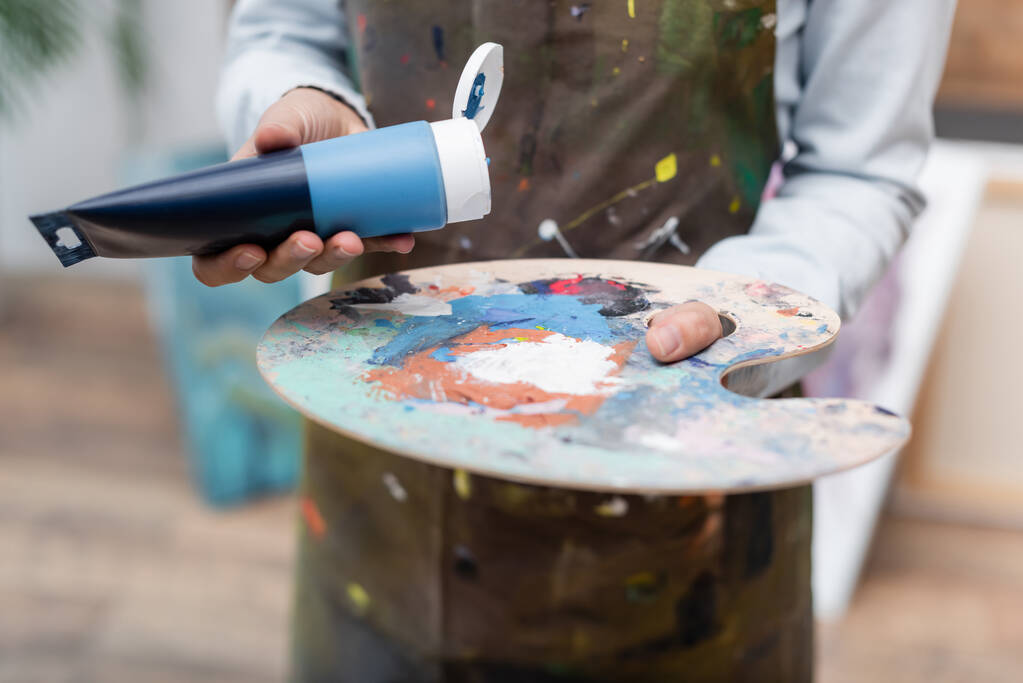 vista cortada de mulher borrada segurando tubo de pintura perto da paleta - Foto, Imagem