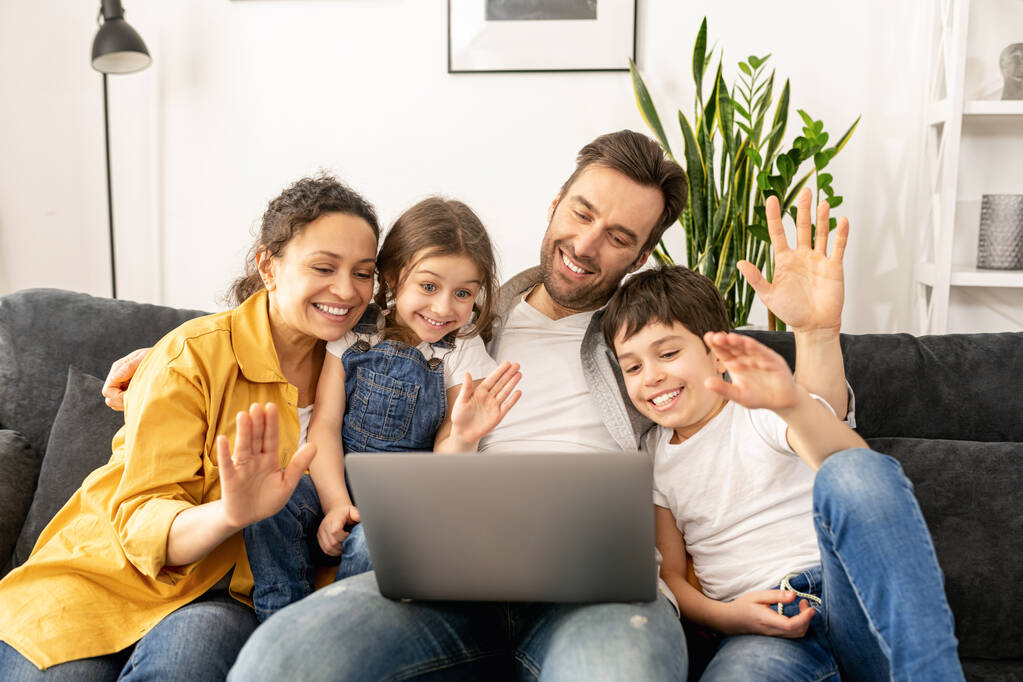Τετραμελής οικογένεια που χρησιμοποιεί φορητό υπολογιστή για σύνδεση βίντεο με παππούδες ή οικογένειες - Φωτογραφία, εικόνα