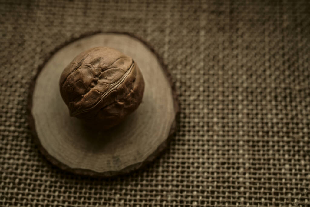 Afgeronde walnoot op een jute op een bruine jute (bovenaanzicht). Ongeschilde walnoot in een schaal op een zak - Foto, afbeelding