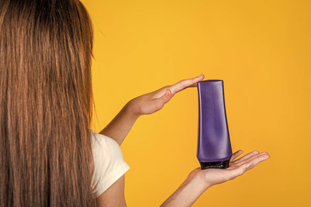Kind Mädchen mit langen glatten Haaren halten Conditioner Shampoo- oder Gelflasche, Haar Gesundheit - Foto, Bild