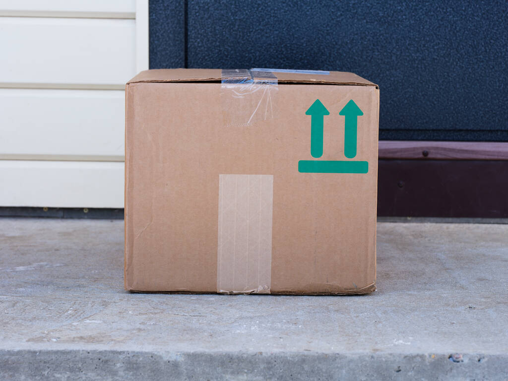 Una caja de cartón entregada a la puerta de la casa. Sign This Way Up impreso en caja. - Foto, imagen