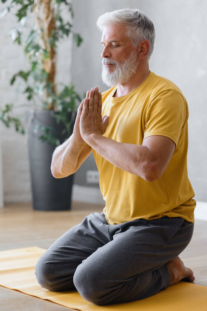 uomo con i capelli grigi medita e fa esercizi di respirazione. fitness sportivo ed esercizi fisici per anziani - Foto, immagini